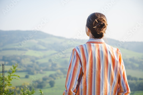 A woman with a chignon is looking at the Montefeltro hills, in the Marche Region of Italy, near Pesaro and Urbino during a nice sunny autumn afternoon