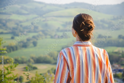 A woman with a chignon is looking at the Montefeltro hills, in the Marche Region of Italy, near Pesaro and Urbino during a nice sunny autumn afternoon