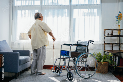 Asian senior old man with wheelchair walking with walker cane stick in nursing home, elderly mature disabled man patient, elderly health care concept. photo