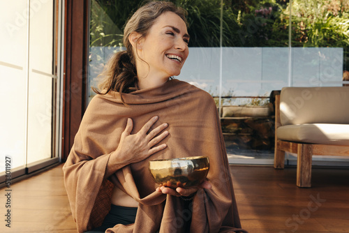 Cheerful senior woman smiling happily while holding a singing bowl