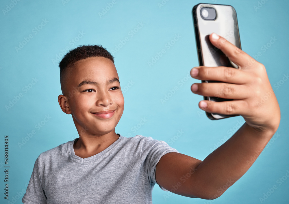 .Phone, selfie and boy child with happy smile for confident and carefree digital photograph fun. Cheerful male preteen smiling for smartphone camera picture with blue background for mock up. .Phone, selfie and boy child with happy smile for confident and carefree digital photograph fun. Cheerful male preteen smiling for smartphone camera picture with blue background for mock up.