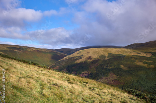 Warm sunlight on Loft Hill below the cloud covered Windy Gyle in the Cheviot Hills in Northumberland, England, UK. photo