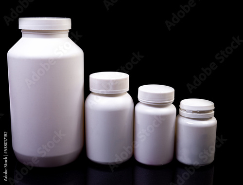 Medical pills in white jar on an isolated black background with reflection