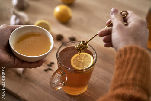 Close up of caucasian woman preparing autumn tea with honey photo