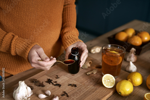 Sick woman preparing syrup for flu at autumn season