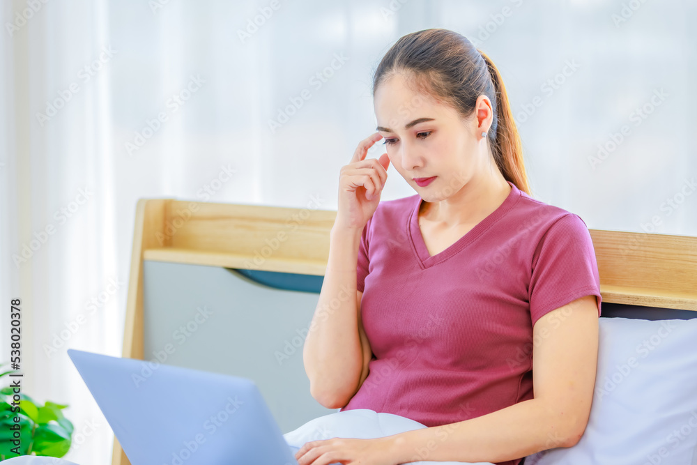 Millennial Asian young happy cheerful female housewife sitting smiling on bed and pillow under thick warm blanket using laptop notebook computer browsing surfing internet shopping online in bedroom Millennial Asian young happy cheerful female housewife sitting smiling on bed and pillow under thick warm blanket using laptop notebook computer browsing surfing internet shopping online in bedroom