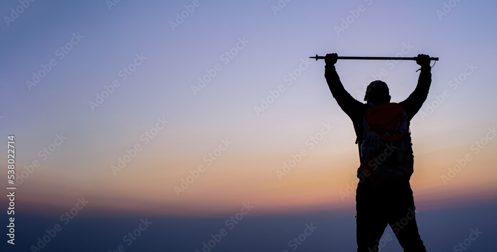 Silhouette of cheering hiking man open arms to the sunrise stand on mountain