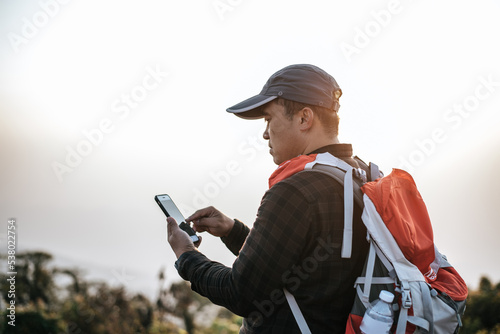 Fototapeta Naklejka Na Ścianę i Meble -  Portrait of Hiker man with backpack using smartphone