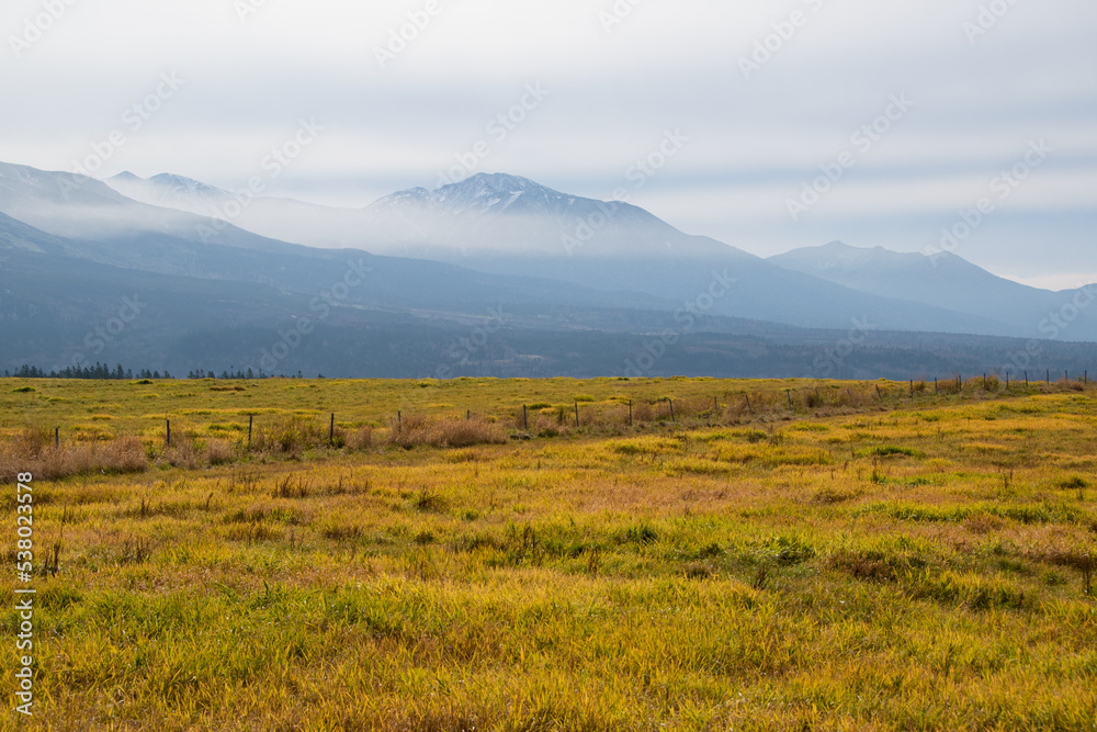 秋の草原と霞がかかった高い山
