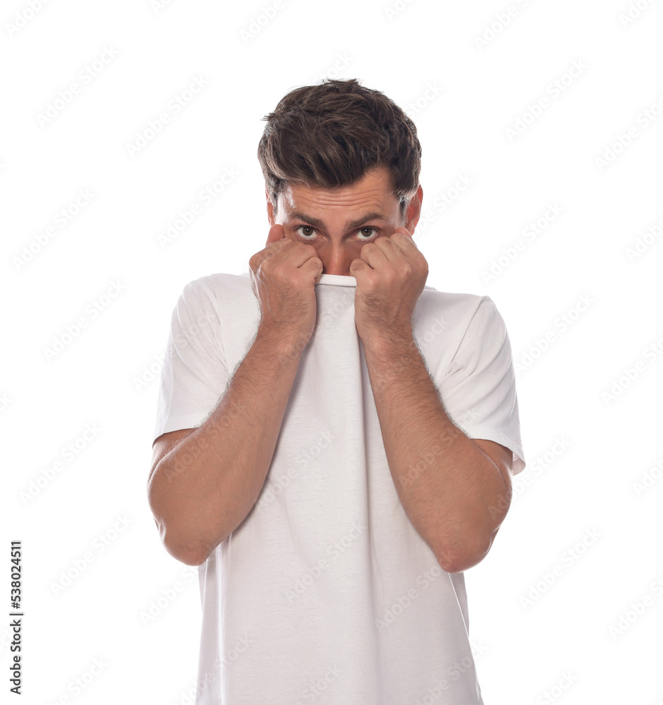 Embarrassed man covering face with shirt on white background Embarrassed man covering face with shirt on white background