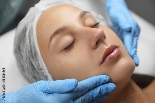Young woman receiving facial massage in salon, closeup,