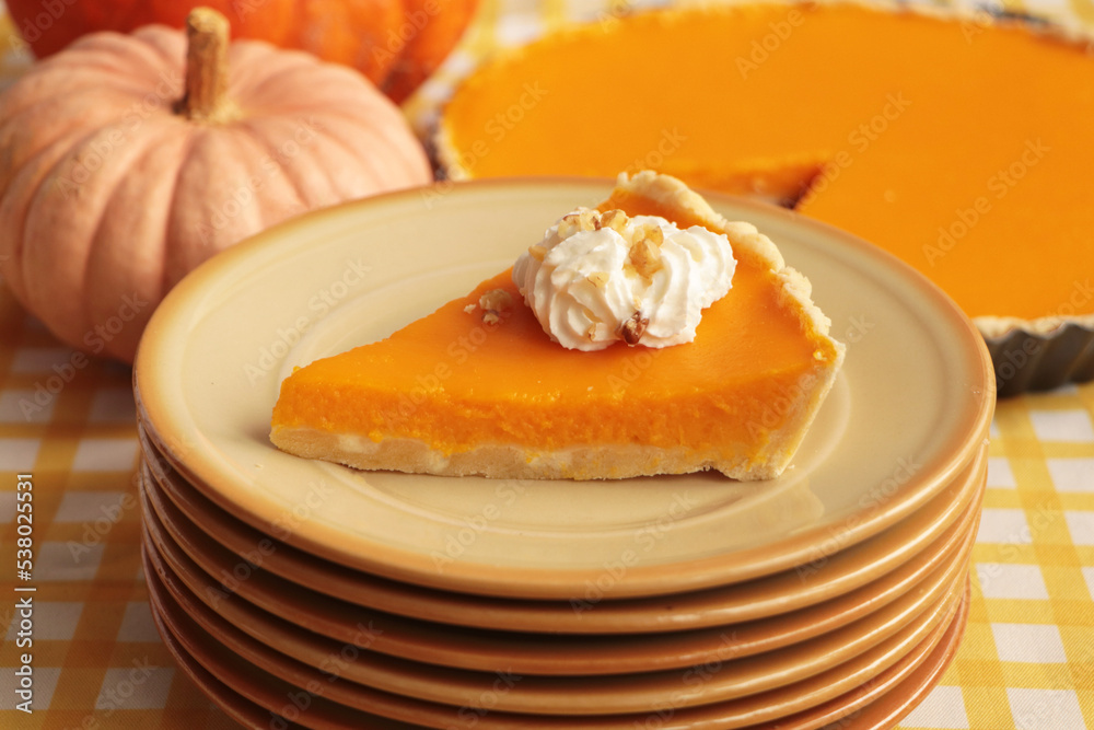 Stacked plates with piece of fresh homemade pumpkin pie with whipped cream on table Stacked plates with piece of fresh homemade pumpkin pie with whipped cream on table
