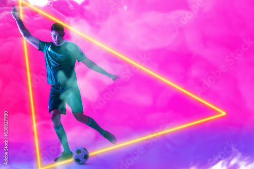 Caucasian male player playing with ball over illuminated triangle against pink neon background