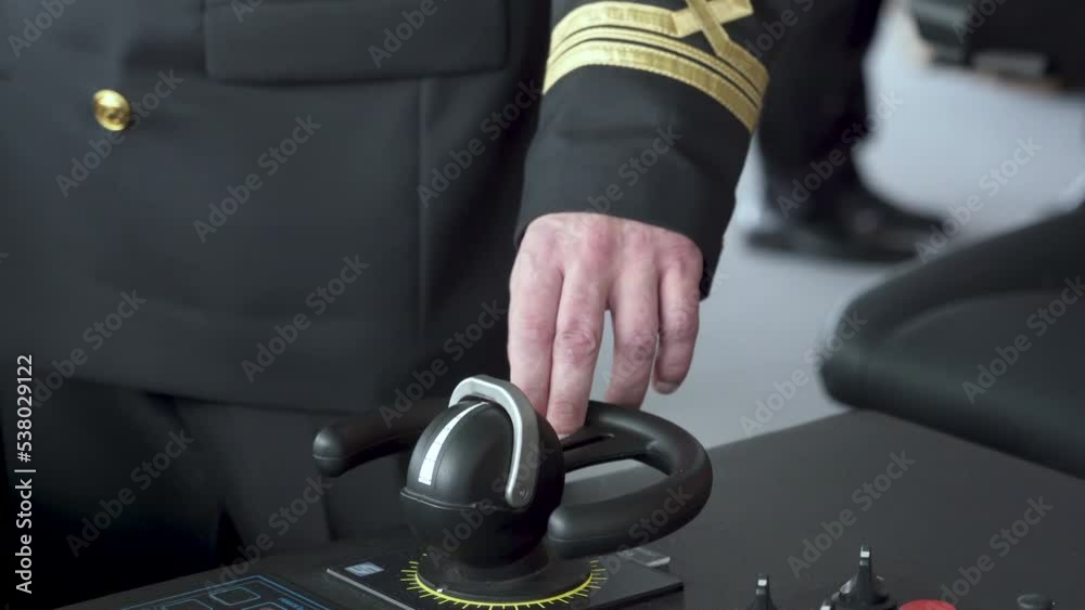 Vessel's bridge. Officer turns controller of bow thruster. Second mate