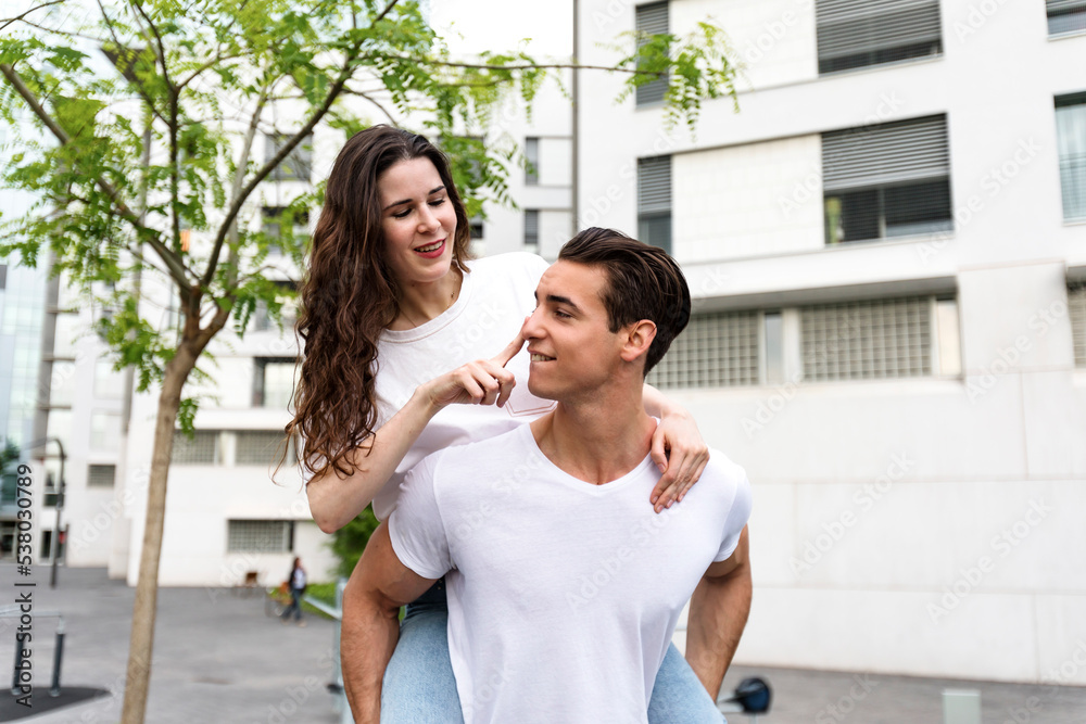 Man and woman couple piggyback and hugging each other at street Man and woman couple piggyback and hugging each other at street