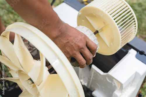 A repairman removes the motor, blower and condenser fan from a window type AC. Air conditioner repair.