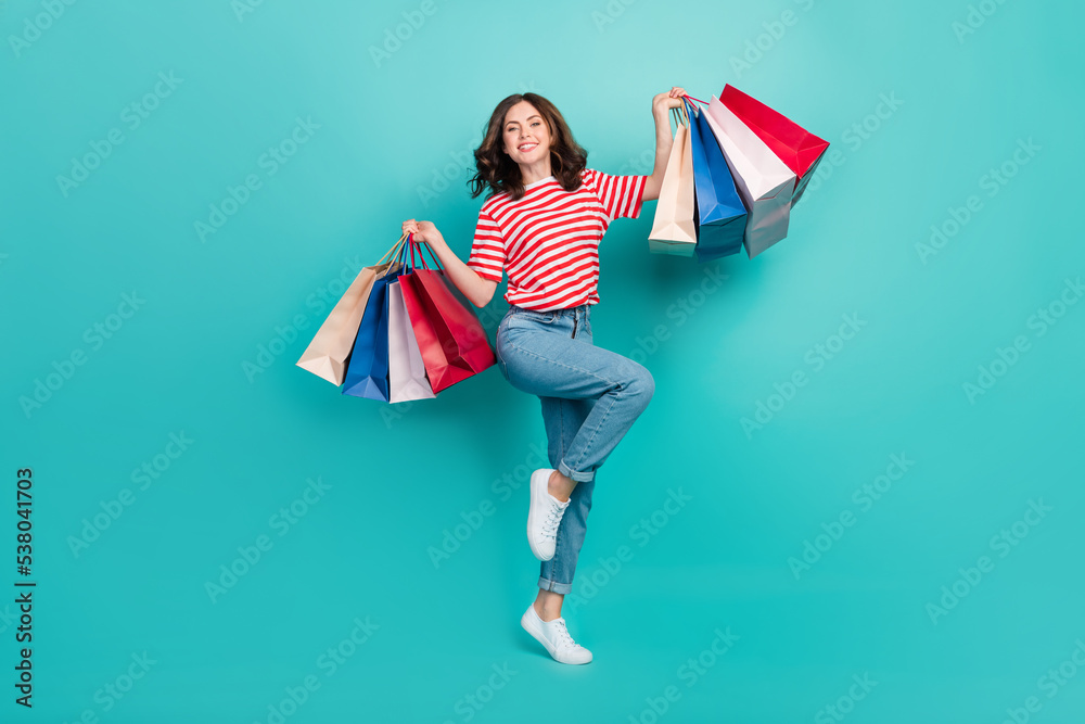 Full length photo of cute sweet lady wear striped t-shirt rising shopping bargains isolated turquoise color background Full length photo of cute sweet lady wear striped t-shirt rising shopping bargains isolated turquoise color background