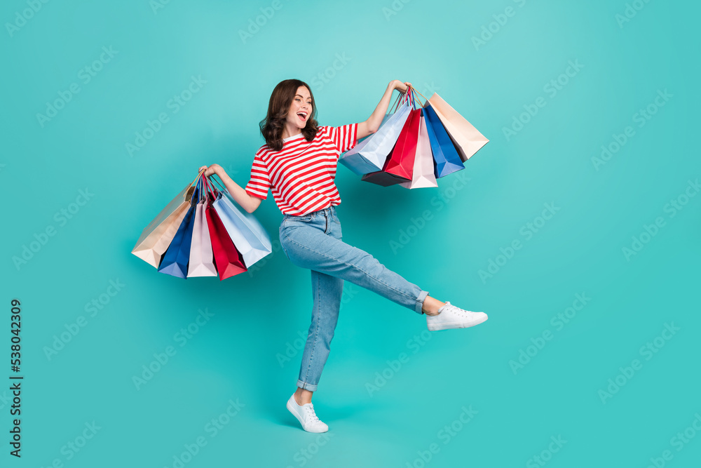 Full length photo of pretty cute lady wear striped t-shirt walking shopping looking empty space isolated turquoise color background Full length photo of pretty cute lady wear striped t-shirt walking shopping looking empty space isolated turquoise color background