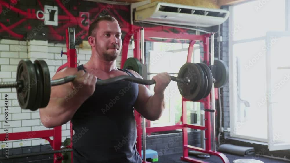 Close up of an attractive man bodybuilder performing barbell biceps curls Close up of an attractive man bodybuilder performing barbell biceps curls
