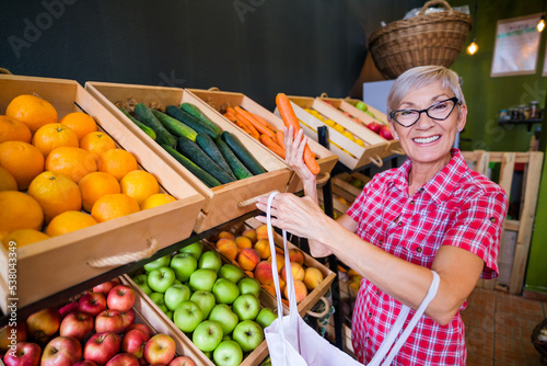 Mature woman buying goods in fruits and vegetables shop.