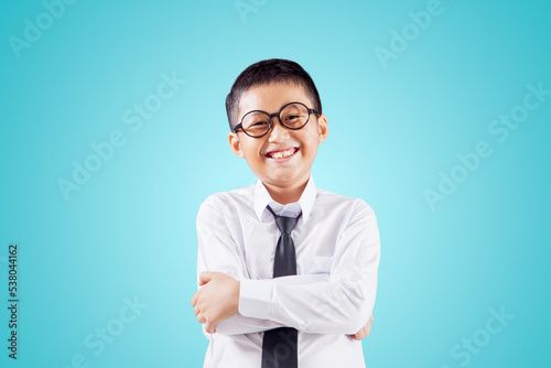 Foto Cheerful schoolboy crossing hands on studio