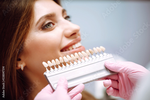 Tooth whitening, perfect white teeth close up with shade guide bleach color. Healthy teeth and medicine concept.
