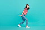 Full length photo of positive funky lady arm hold big object empty space dressed striped stylish clothes isolated on cyan color background