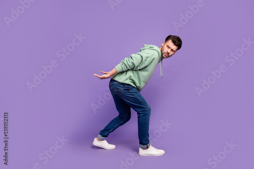 Full body photo of attractive young man carry look suspicious empty space dressed stylish khaki garment isolated on purple color background