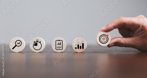 Target or goal with strategy plan, success business revenue concept. Symbols of arrows, diagrams businesses are present on wood cube. objective management, achievement startup, growth marketing idea.