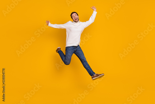 Photo of funky childish guy dressed white sweater running jumping high isolated yellow color background