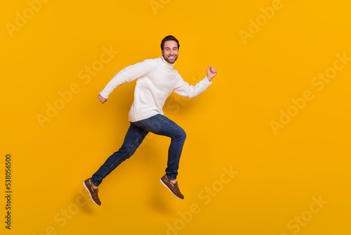 Photo of pretty excited guy dressed white sweater running fast jumping high isolated yellow color background