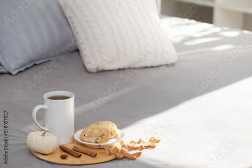cup of coffee on wooden tray on bed in cozy bedroom
