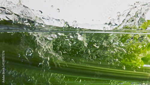 Ripe celery splashing liquid in light background closeup. Healthy fitness eating