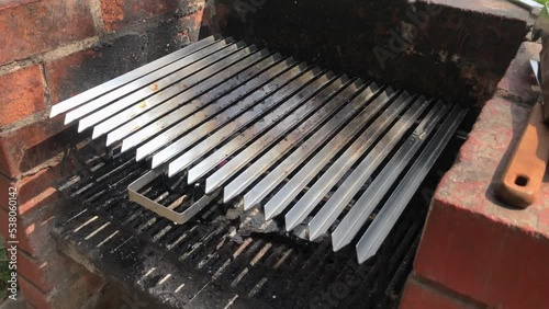 4k video of a brick barbecue. The iron silver grill sits above hot charcoal. Recorded on a sunny day. photo