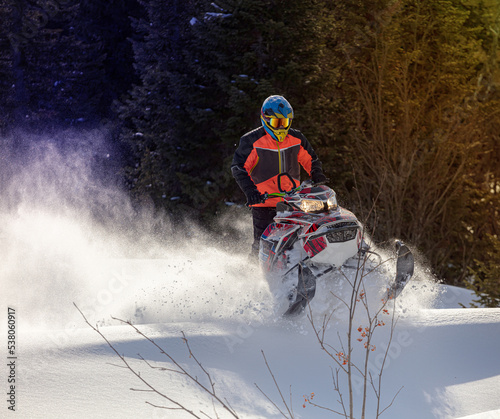 snowmobile fun. sports snow bike with snow splashes and snow trail. bright snowmobile and suit without brands. snowmobilers sports riding. stock photo very high quality