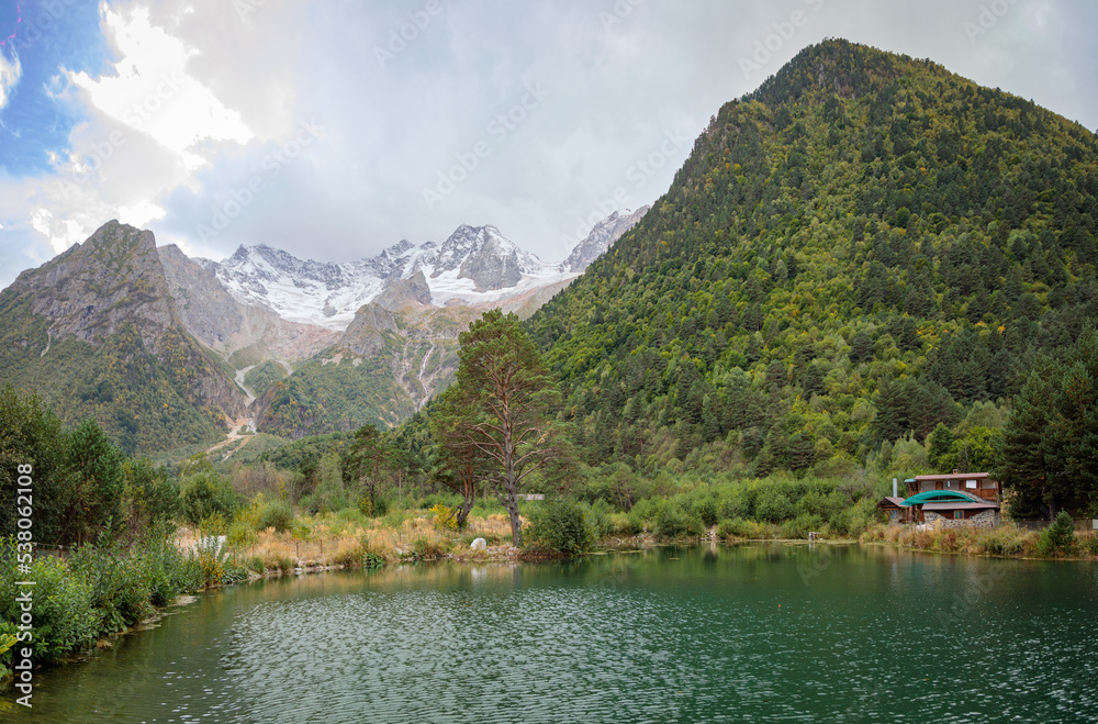 Mountain landscape with a glacier in the distance. Lake in the mountains. Tana glacier in Ossetia. Mountain landscape with a glacier in the distance. Lake in the mountains. Tana glacier in Ossetia.