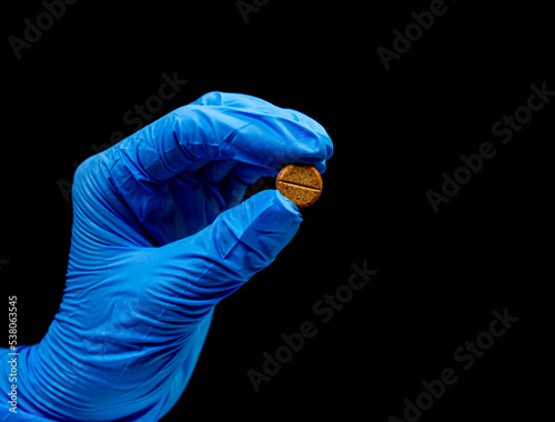 Medical pills on isolated black background with reflection in hand