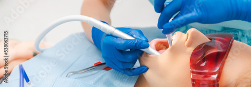 Close up panorama shot of a dentist examining a woman mouth with some tools.