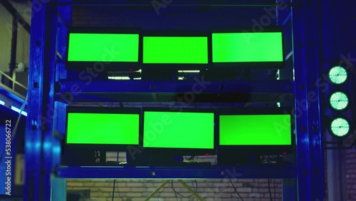 A lot of monitors with green screen in dark modern room. Concept of monitoring , trading , analysing room and security systems . Video Switcher , many Screens for Broadcasting Live at Tv Control place photo