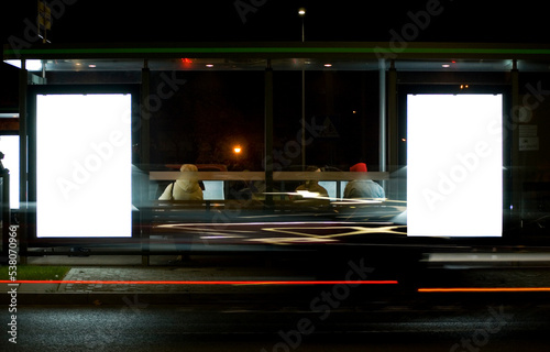 Outdoor advertising billboards at tramway stop at nighttime in the city.