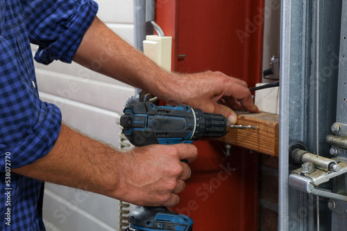 Close up on man caucasian hand holding electric cordless screwdriver working indoor screwing technician on wood inside site work using hand tools concept.