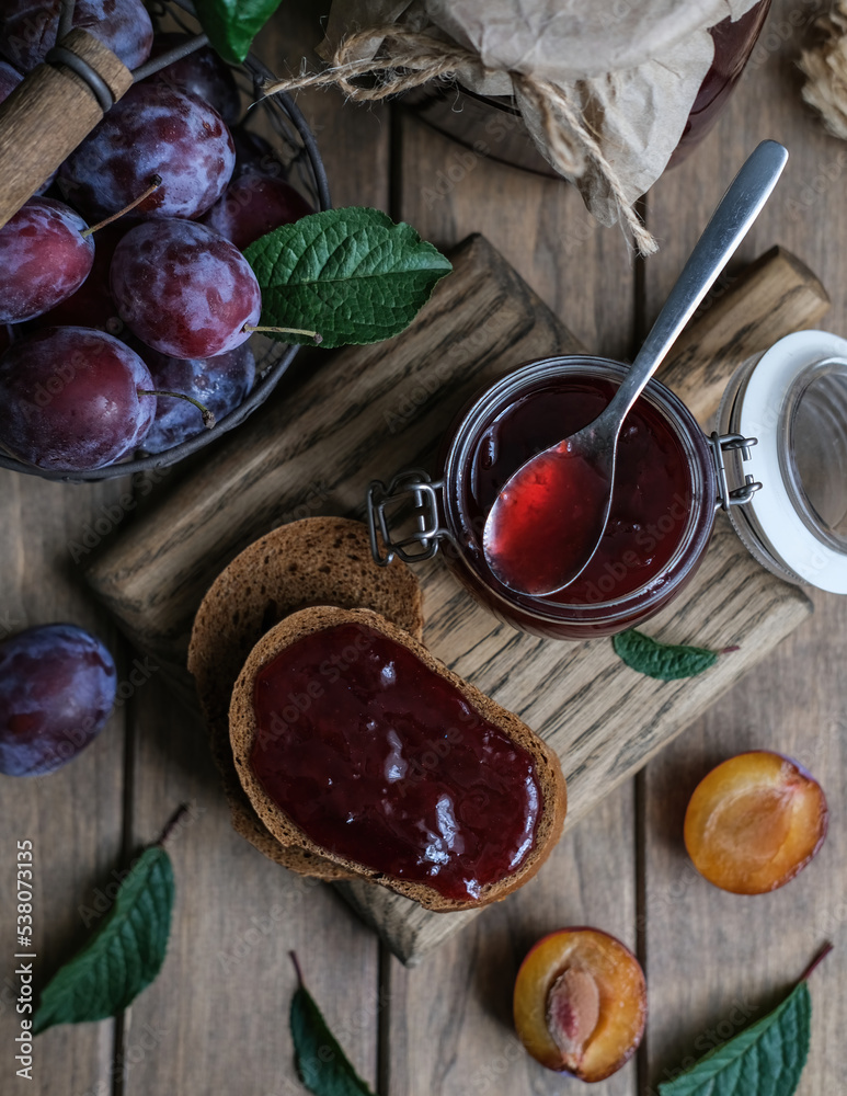Homemade plum jam and fresh berries on a wooden background. Homemade preserving concept. Summer seasonal berry jams Homemade plum jam and fresh berries on a wooden background. Homemade preserving concept. Summer seasonal berry jams