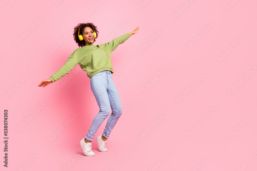 Full body photo of young excited girl have fun playful look empty space listen headphones isolated over pink color background