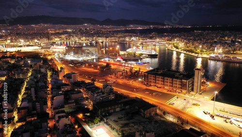 Aerial drone night shot of passenger ferry arriving to famous passenger port of Piraeus one of the largest in Europe, Attica, Greece