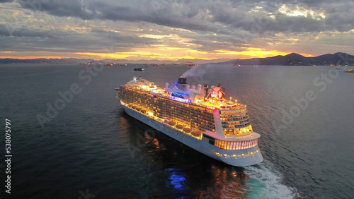 Obraz na płótnie Aerial drone photo of huge illuminated cruise liner ship cruising to popular Aegean destinations at dusk with beautiful colours w salonie