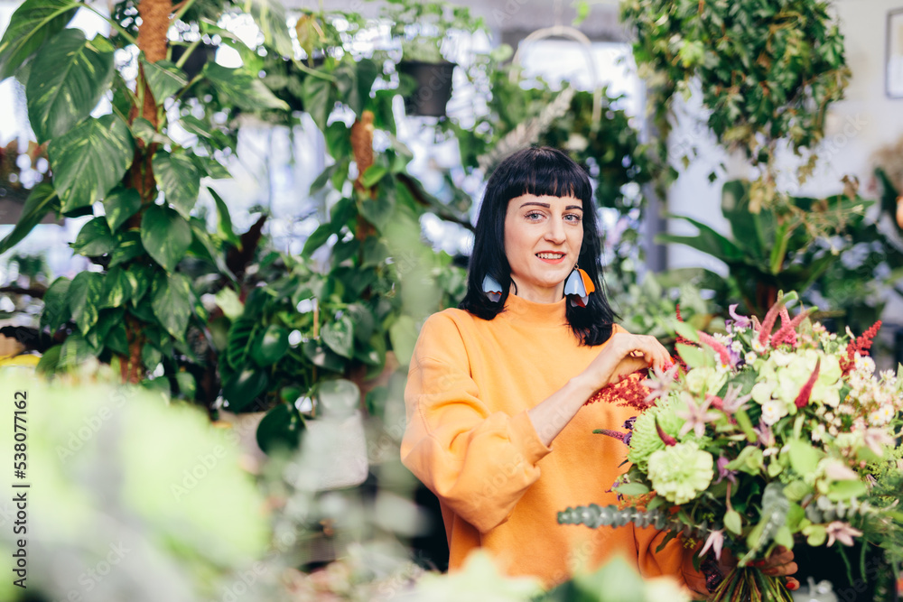 Woman arranges bouquet from flowers in florist shop Woman arranges bouquet from flowers in florist shop