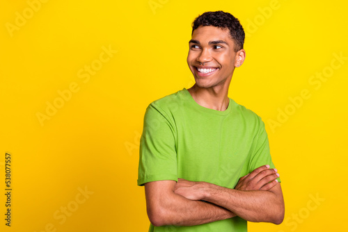 Photo of young attractive handsome cute smile confident guy crossed hands look interested empty space good news information ad isolated on yellow color background