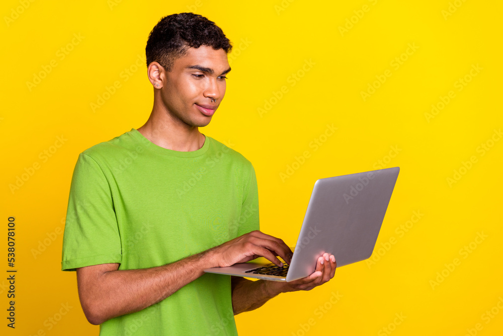 Photo of young handsome confident professional user hold new laptop concentrated marketology isolated on yellow color background Photo of young handsome confident professional user hold new laptop concentrated marketology isolated on yellow color background