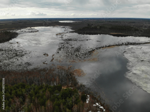 Spring lake with ice in forest. Aerial drone view. Flying over. Drone is moving. High quality photo