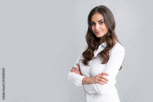 Pretty woman dressed casually in shirt looking with satisfaction. Studio shot of beautiful woman isolated against gray background.